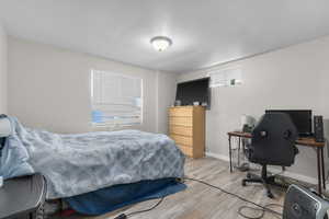 Bedroom with wood finished floors and a desk
