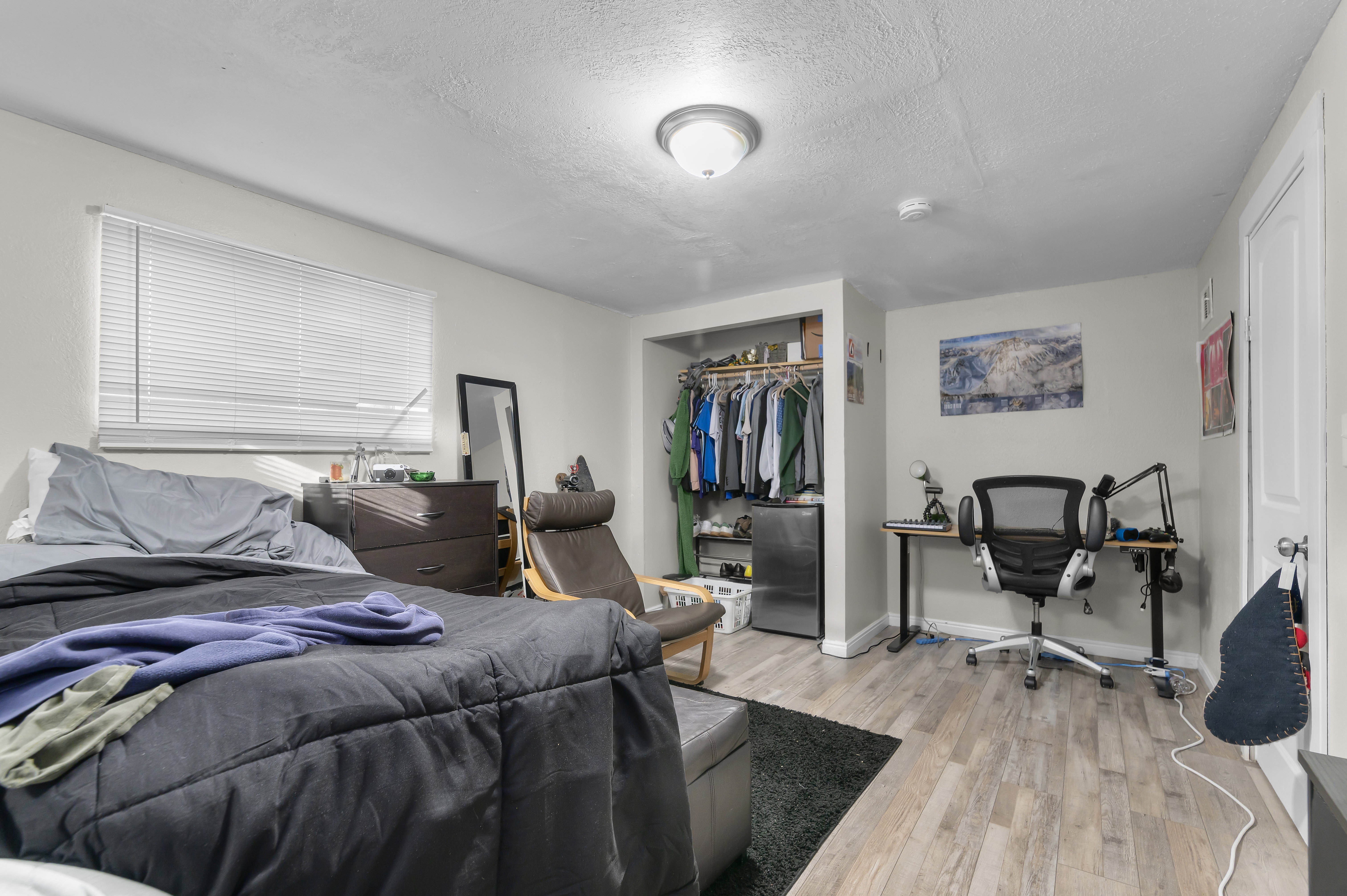 Bedroom with a textured ceiling, a closet, light wood-style floors, freestanding refrigerator, and an office area