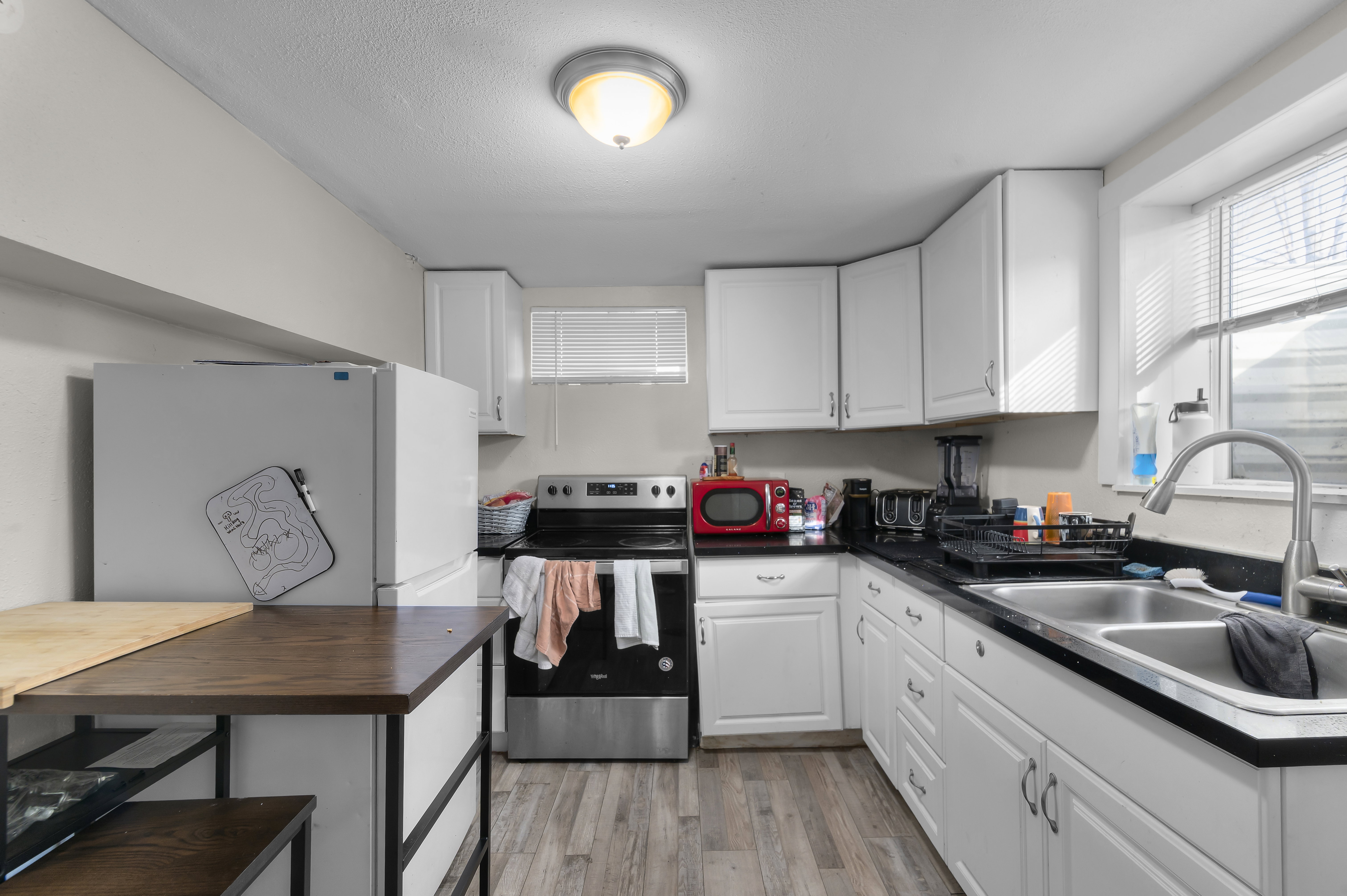 Kitchen featuring dark countertops, stainless steel range with electric cooktop, freestanding refrigerator, white cabinetry, and a textured ceiling