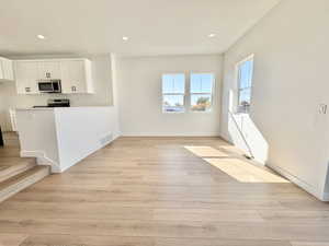 Kitchen with white cabinetry, recessed lighting, light wood-style floors, light countertops, and a peninsula