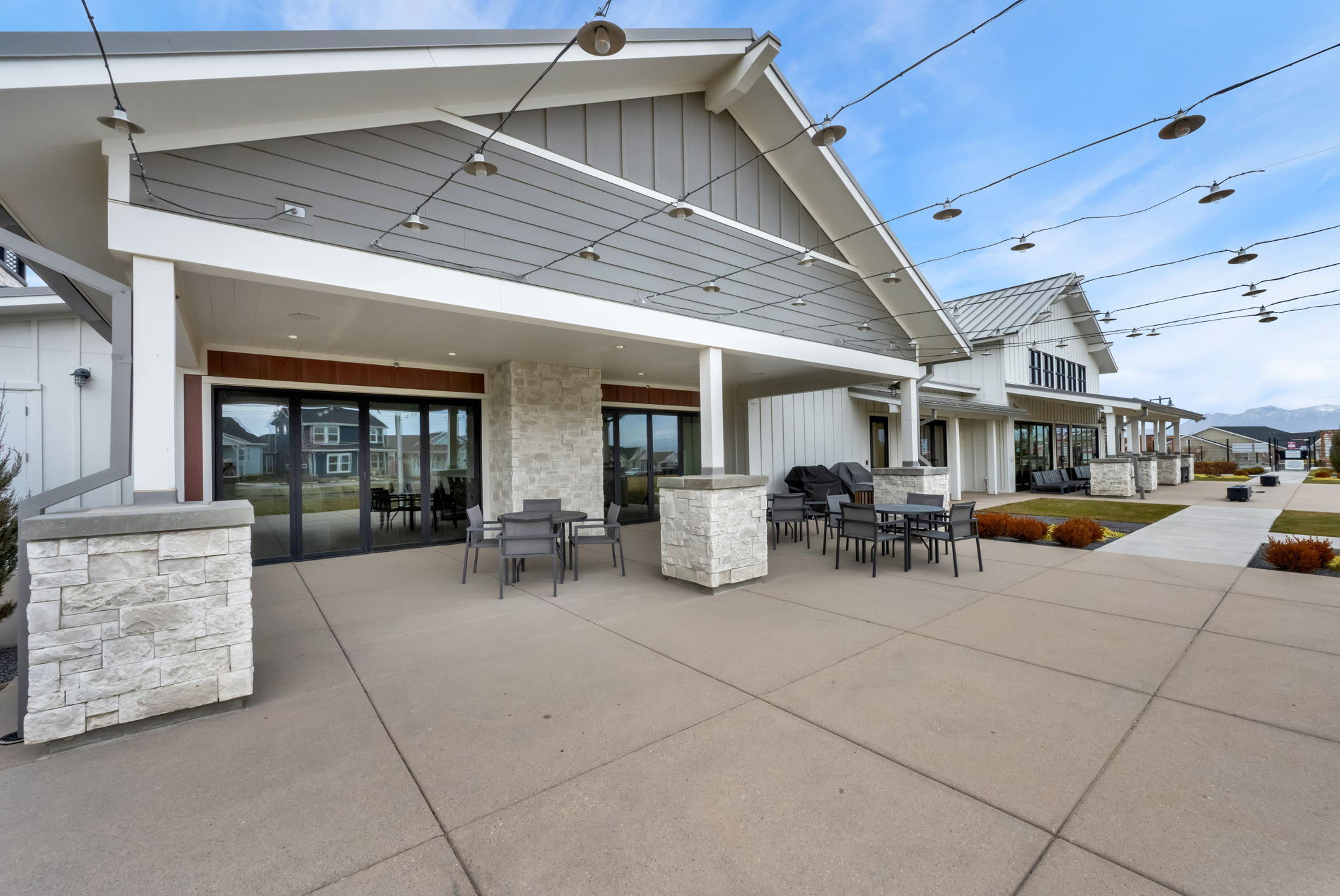 Rear view of house with a patio area, outdoor dining space, board and batten siding, and stone siding