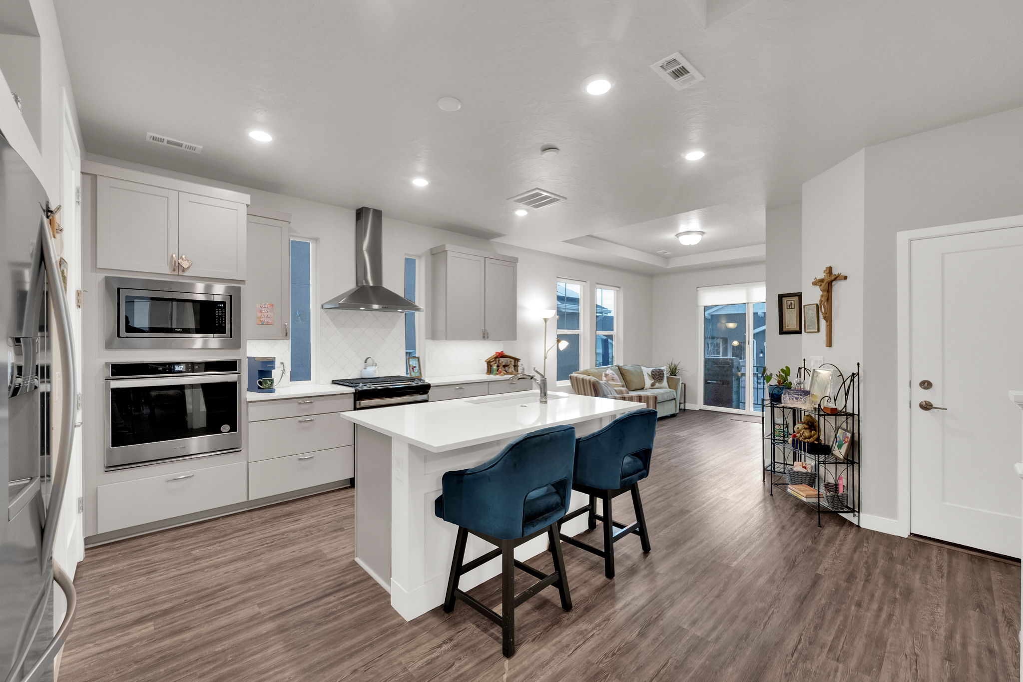 Kitchen with a kitchen breakfast bar, appliances with stainless steel finishes, wall chimney range hood, an island with sink, and decorative backsplash