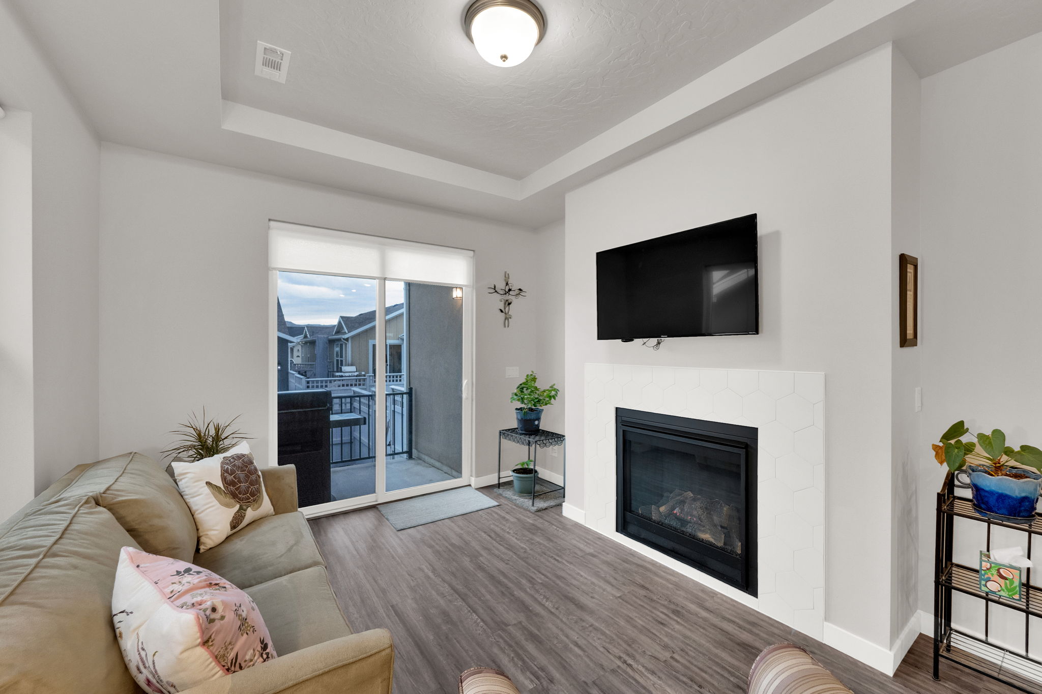 Living area with a tray ceiling, wood finished floors, and a glass covered fireplace