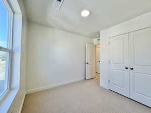 Unfurnished bedroom with light carpet, a textured ceiling, and a closet