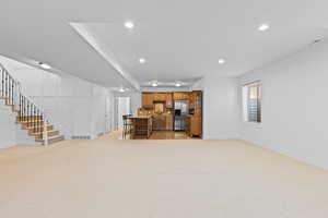 Living area featuring stairs, light carpet, and recessed lighting