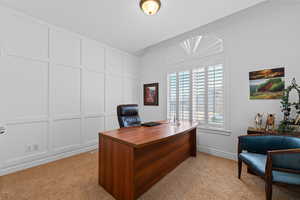 Office space with a decorative wall and light colored carpet