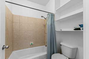 Bathroom featuring shower / bathtub combination with curtain and toilet