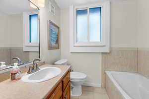 Full bathroom featuring vanity, a bath, and light tile patterned flooring