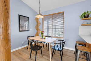 Dining area featuring vaulted ceiling and light wood-style floors