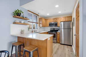 Kitchen with appliances with stainless steel finishes, a peninsula, a breakfast bar area, open shelves, and backsplash