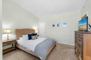 Bedroom with light carpet and lofted ceiling