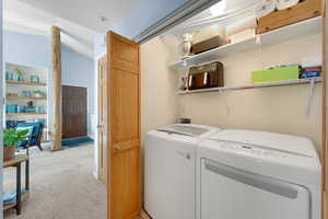 Laundry area with lofted ceiling, light carpet, and washer and dryer