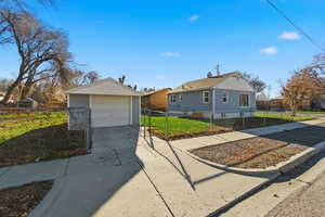 View of side of property with driveway, a fenced front yard, an outdoor structure, and a detached garage