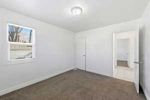 Unfurnished bedroom with carpet flooring and baseboards