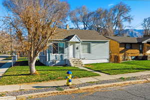 View of front of property with a front lawn, a chimney, entry steps, and a shingled roof
