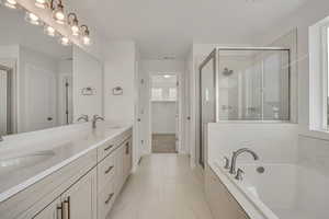 Bathroom featuring a stall shower, double vanity, a spacious closet, and a garden tub