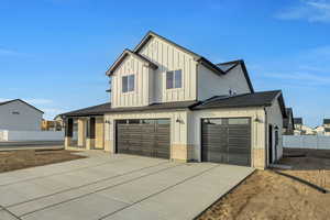 Modern farmhouse style home with driveway, a garage, board and batten siding, and brick siding