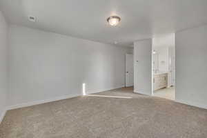 Unfurnished bedroom featuring light carpet and ensuite bath
