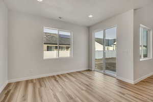 Spare room featuring light wood-type flooring, plenty of natural light, and recessed lighting
