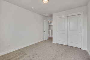 Unfurnished bedroom featuring light colored carpet and a closet