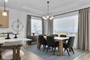 Dining area featuring light wood-style floors, a raised ceiling, and a chandelier