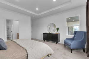 Carpeted bedroom featuring a raised ceiling, recessed lighting, ensuite bath, and a spacious closet