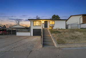 View of front of house featuring driveway, a garage, brick siding, and stairs