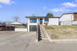 View of front facade featuring a garage, driveway, brick siding, and a carport