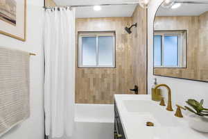 Bathroom featuring vanity and shower / bathtub combination with curtain