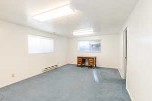 Carpeted empty room with a baseboard heating unit and a textured ceiling