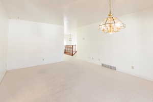 Carpeted spare room featuring a chandelier