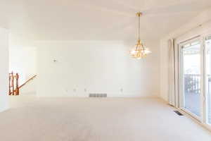 Unfurnished room with carpet flooring and a chandelier
