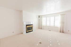 Unfurnished living room featuring a fireplace, light carpet, and a textured ceiling