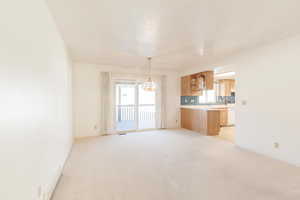 Unfurnished living room with light carpet and a chandelier