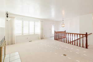 Empty room with light carpet and a chandelier