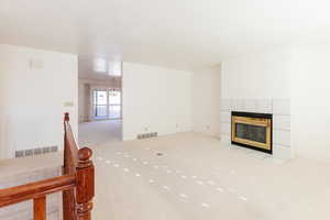 Unfurnished living room with a fireplace, light carpet, and a chandelier