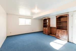 Unfurnished living room featuring carpet flooring and a textured ceiling
