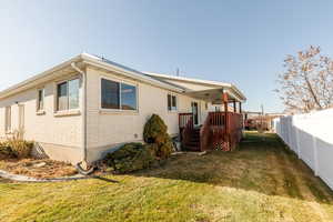 Rear view of house with a fenced backyard, a wooden deck, and brick siding