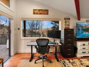 Office with light wood-type flooring and lofted ceiling