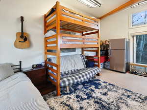 Bedroom featuring freestanding refrigerator and light colored carpet