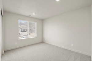 Carpeted empty room featuring a textured ceiling and recessed lighting