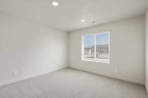 Empty room with light carpet, recessed lighting, and a textured ceiling