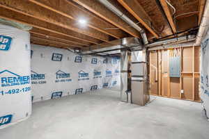Unfinished below grade area with electric panel and heating unit