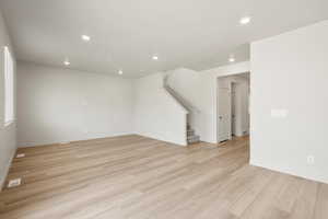 Unfurnished living room featuring recessed lighting, light wood finished floors, and stairs
