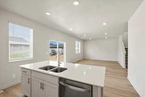 Kitchen featuring a center island with sink, stainless steel dishwasher, light wood-type flooring, recessed lighting, and white cabinetry