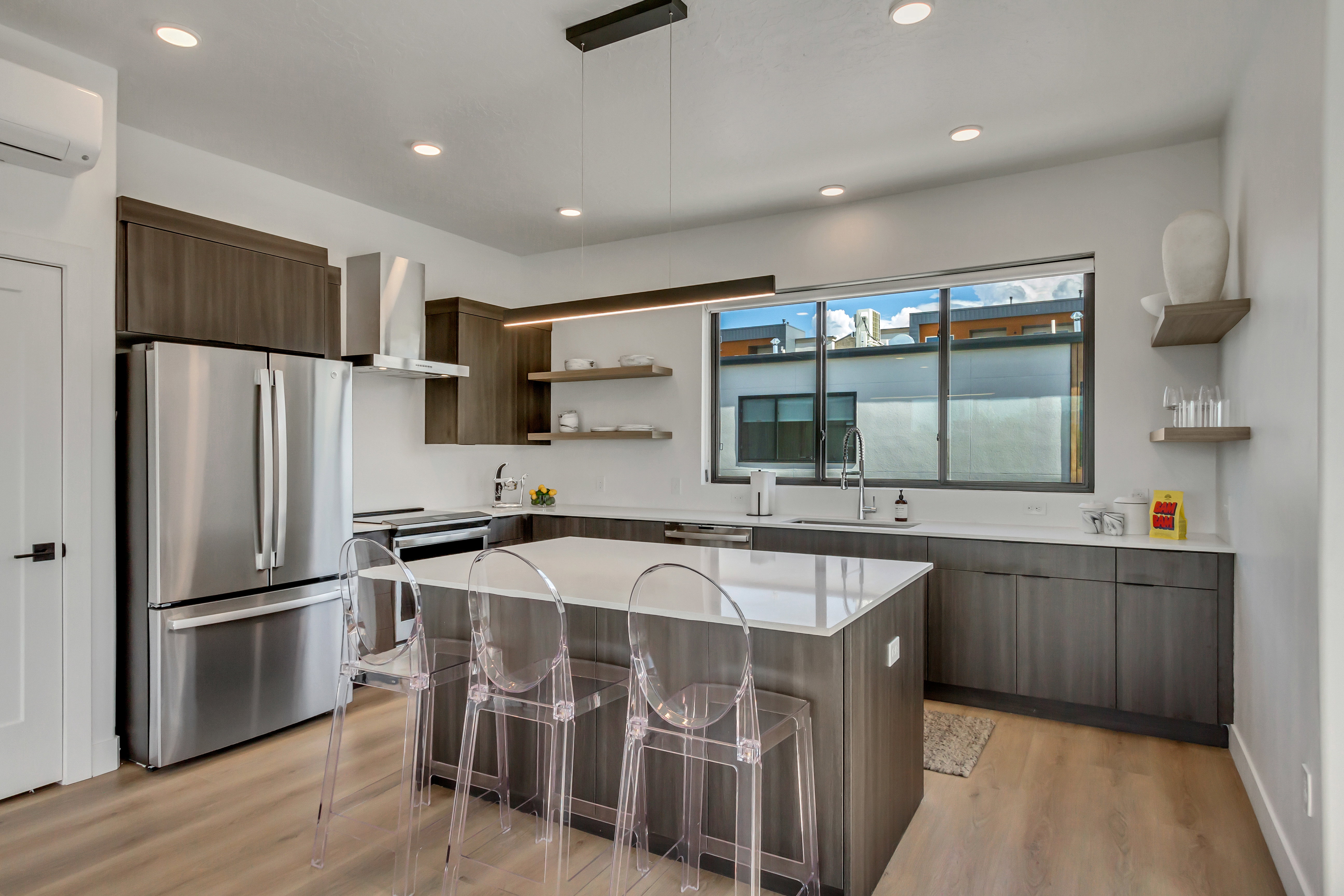 Kitchen with open shelves, a kitchen bar, appliances with stainless steel finishes, dark brown cabinetry, and modern cabinets