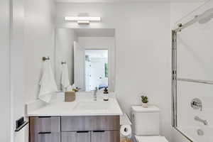 Ensuite bathroom featuring vanity and bath / shower combo with glass door