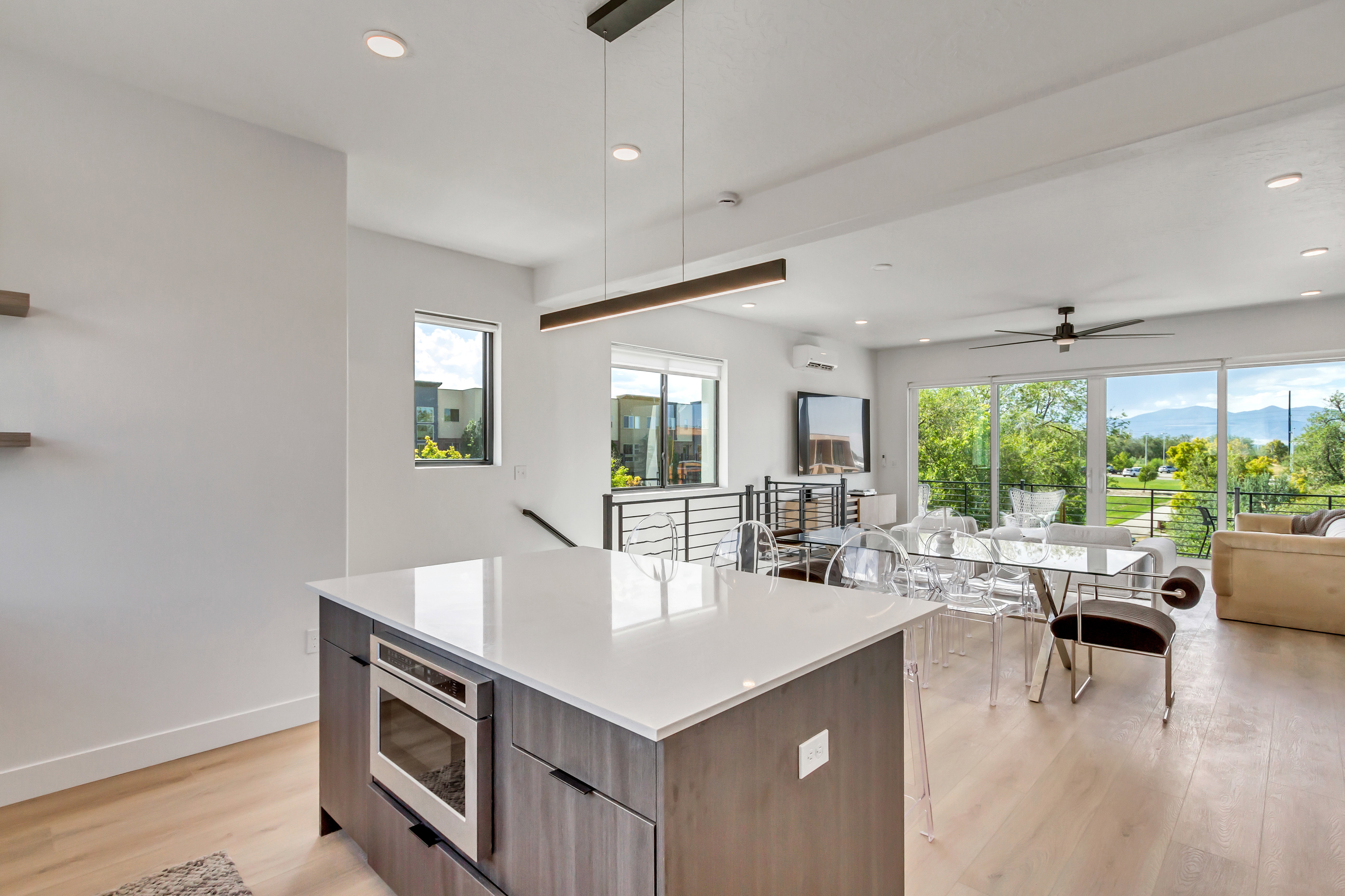 Kitchen featuring modern cabinets, decorative light fixtures, open floor plan, light wood-type flooring, and a kitchen island