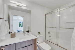 Ensuite bathroom with bath / shower combo with glass door and vanity