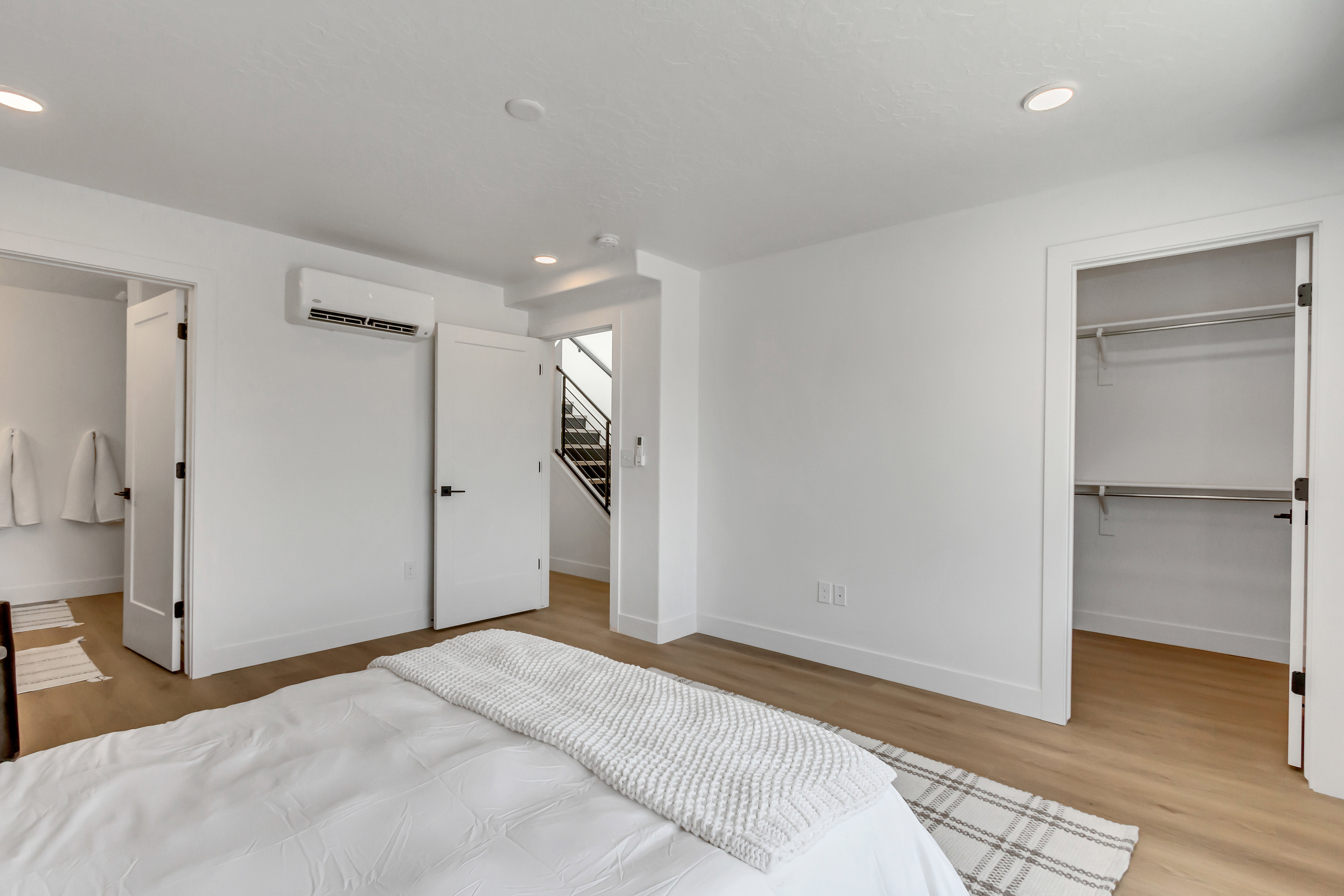 Bedroom featuring a spacious closet, light wood-style flooring, recessed lighting, and a wall mounted AC